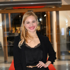 Vynesla černé šaty se zlatým páskem. 