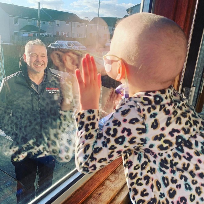 Mila Sneddon zaujala princeznu Kate roku 2020, kdy tuto fotku zahlédla při kompletování knihy, mapující život v Británii během covidu. Tehdy čtyřletá holčička podstupovala chemoterapii kvůli onemocnění leukémií, a protože tatínek musel chodit do práce, nesměl se k ní přiblížit, aby ji náhodou nenakazil.