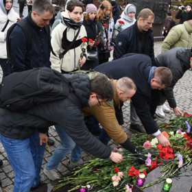 Lidé nosí za oběti květiny a svíčky.