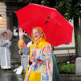 Signifikantní pršiplášť a čapka proti dešti, které si královna Markéta II. sama navrhla a oblékla v letech 1995 a 2017. Outfit byl komplet vyroben z povoskovaného omyvatelného ubrusu.