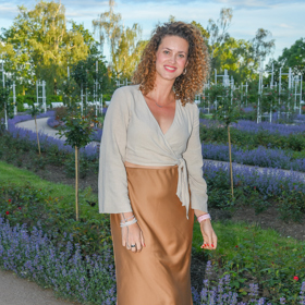 Zpěvačka Kateřina Pechová kombinuje hnědou saténovou sukni s béžovým topem s dlouhým rukávem.