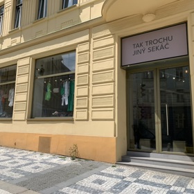 Nenápadné logo zdobí vchod do netradičního obchodu s módou z druhé ruky Tak trochu jiný sekáč.