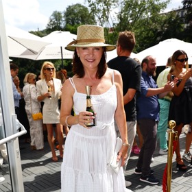 Beata Rajská v létě nosí bílé šaty na špagetových ramínkách, chladí se slamákem a šampaňským. 