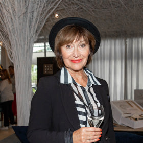 Zpěvačka Petra Černocká nosí velký černý klobouk k černému saku.