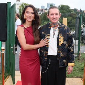 Eva Burešová kombinuje červené šaty s bílými botami na vysoké platformě. Přemek Forejt se rozhodl pro zdobný bomber.