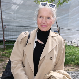 Spisovatelka Irena Obermannová nosí béžový plášť a bílé kalhoty.