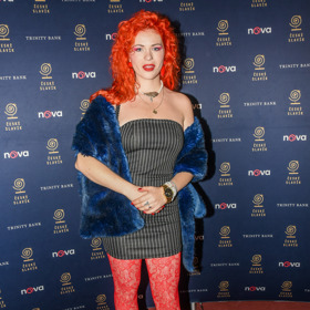 Zpěvačka Žofie Dařbujánová oblékla šedivé minišaty s vertikálními pruhy doplněné o oranžovo-růžové punčochy a modrý umělý kožíšek.