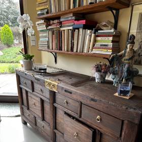 Tmavě hnědá komoda má zlaté kování.