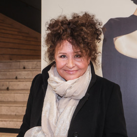 Husté kudrnaté vlasy jsou jako její logo či podpis.