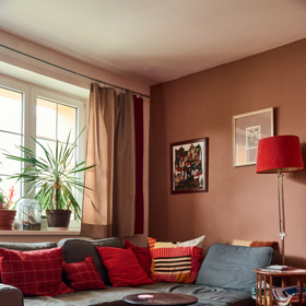 Pohled do obývacího pokoje, který je laděný do červené a hnědé.