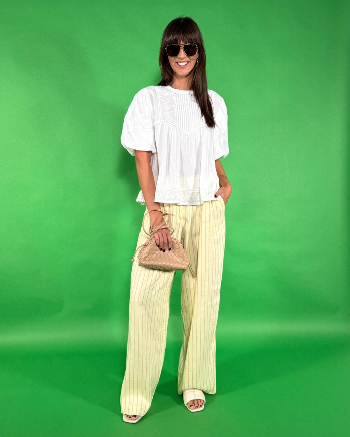 Oblíbený outfit stylistky Nikoly Markové - bílá halenka, pohodlné a lehké kalhoty s proužkem a k tomu hnědé doplňky. 