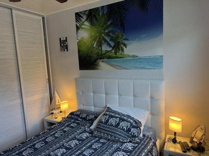 Nad postelí je velký plakát evokující dovolenou u moře.