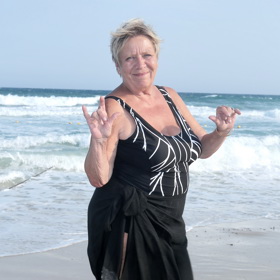 U moře herečka obléká jednodílné černé plavky a dlouhou sukni lemovanou bílou krajkou.