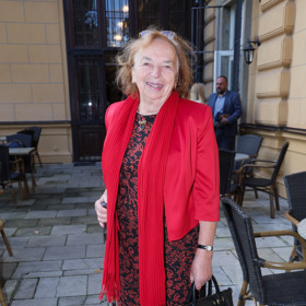 Livia Klausová oblékla červené sáčko i šál a černo-červené šaty doplněné o černou koženou kabelku. Pohodlné černé tenisky jsou pochopitelnou volbou vzhledem k věku bývalé první dámy i místu konání akce. 