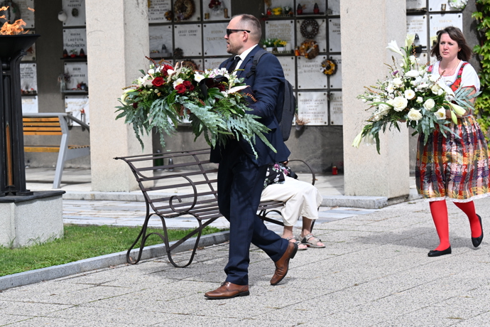 Do smuteční síně se pomalu nosí věnce.