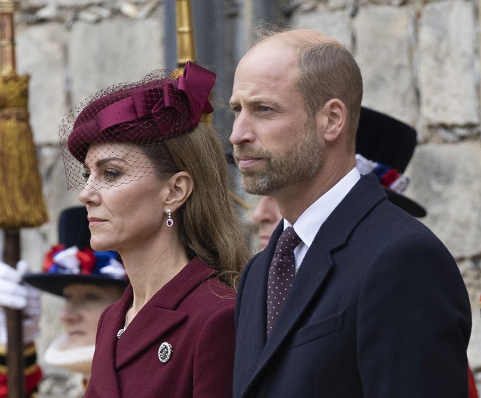 Kabátové šaty doplnila Kate Middleton vínovým kloboučkem Neso z dílny Jane Taylor a náušnicemi s rubínem a diamanty.