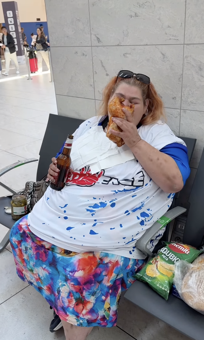 Droběna si na lavičce vychutnává celé kuře a pivo.