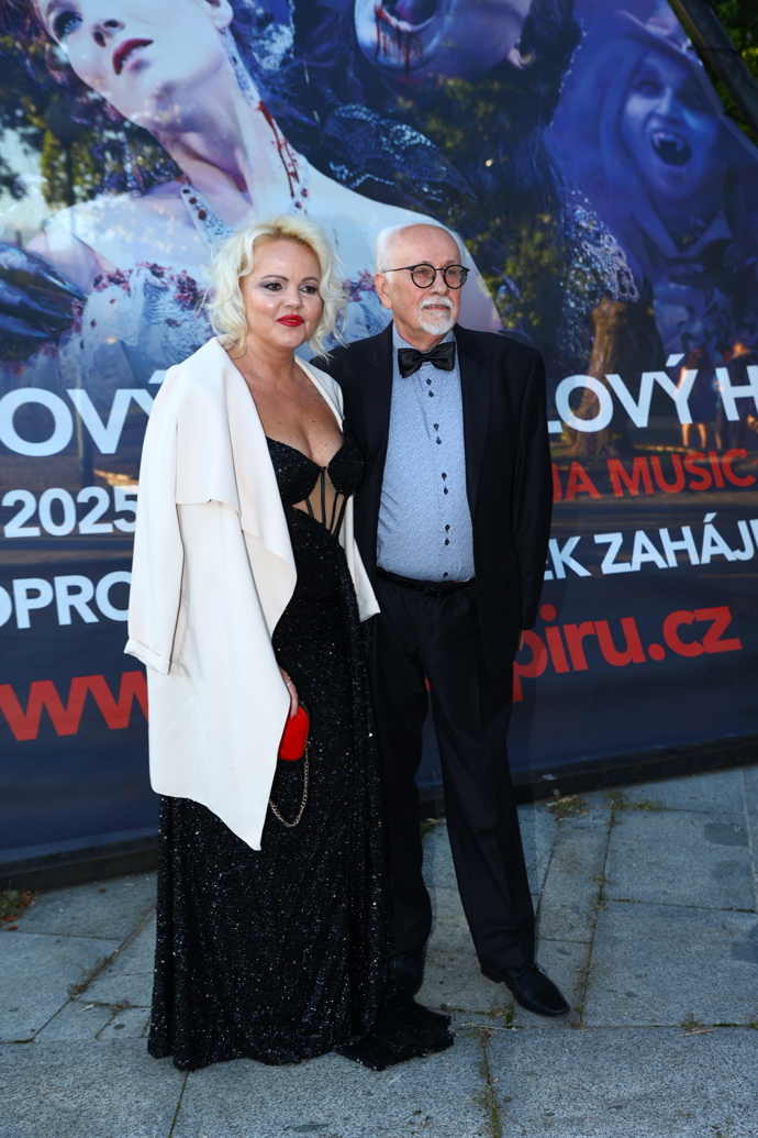 Herec Václav Knop s partnerkou Petrou Bartoňovou, která přes černé šaty korzetového typu oblékla bílé sáčko a outfit doplnila červenou kabelkou i rudými rty.