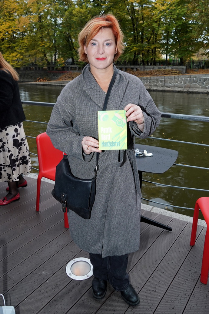 Lenka Krobotová nosí šedý podzimní kabát a černou crossbody kabelku. 