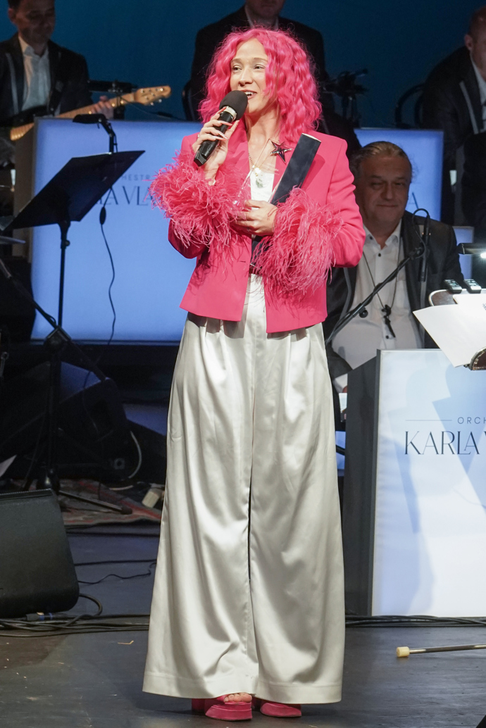 Zpěvačka Tereza Mašková oblékla krémové saténové kalhoty s vysokým pasem a růžové sako s peřím na rukávech. Nechyběly samozřejmě ani její typické, zářivě růžové vlasy.
