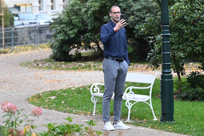 Postával poblíž zahrady, mimo hlavní proud hostů.