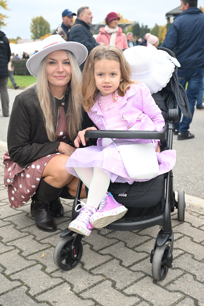 Bílý klobouk s širokou krempou nasadila tato půvabná maminka k hnědým šatům s bílými puntíky.