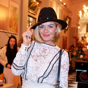 K bílým koktejlkám nosí modelka černý klobouk s užší krempou. 