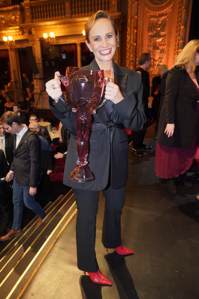 Monika Absolonová oblékla černé smokingové sako v oversize střihu a černé kalhoty a doplnila je o rudé lodičky s uzavřenou špičkou a rudou rtěnku.