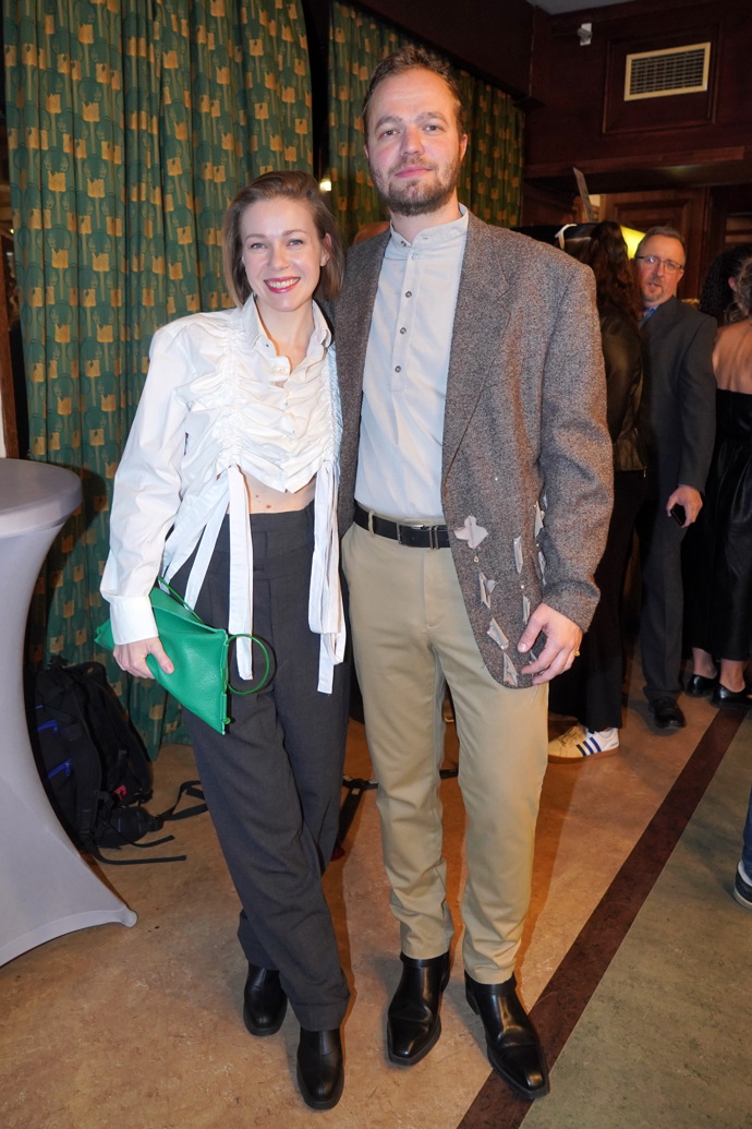 Tomáš Havlínek a Agáta Kryštůfková. Herec oblékl béžové společenské kalhoty, šedou košili a světle hnědé sako s šedými aplikacemi květů. 