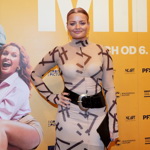 Přes světlé šaty s potiskem a stojáčkem nosí široký pásek herečka Erika Stárková.