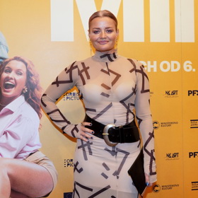 Přes světlé šaty s potiskem a stojáčkem nosí široký pásek herečka Erika Stárková.