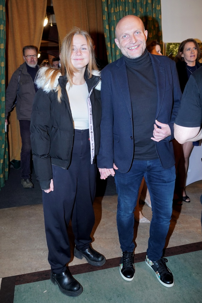 Herec Jiří Ployhar s přítelkyní, která oblékla péřovou bundu, tmavě hnědé kalhoty s vysokým pasem a bílé tričko. 