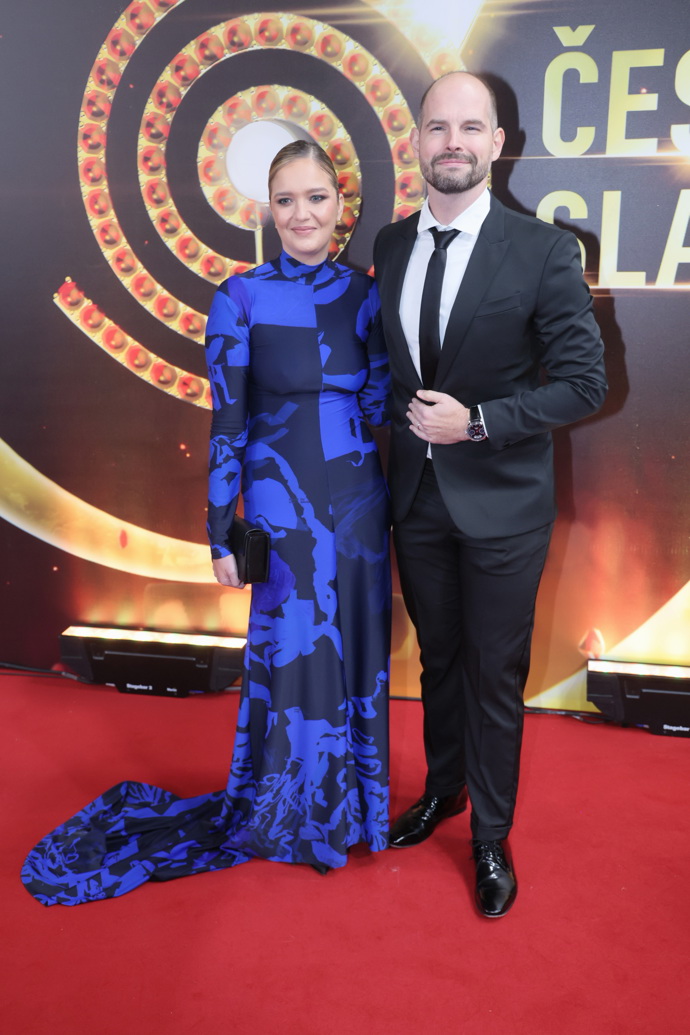 Jan Maxián v doprovodu manželky, která vynesla černo-modré šaty bez výstřihu, ovšem s dlouhou vlečkou. 