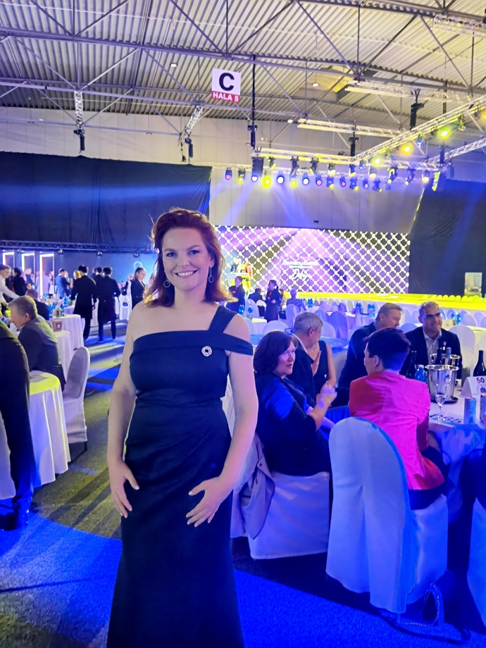 Kvízová dáma vynesla smaragdově zelenou róbu ozvláštněnou jednou ze svých broží. 