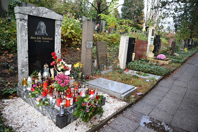 Hrob je obsypán květinami a svíčkami.