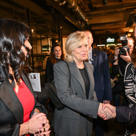 První dáma v elegantním šedém kostýmku.