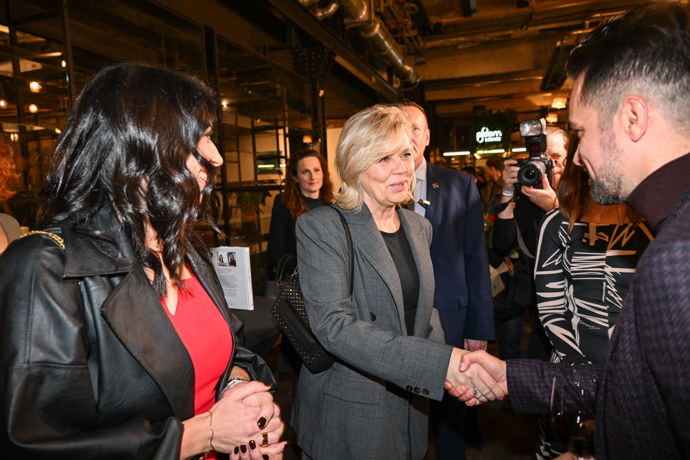 První dáma v elegantním šedém kostýmku.