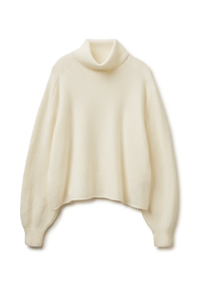 Nenápadnou, ale klíčovou součástí outfitu je i krémový svetr s rolákovým límcem. Tento oversize kousek koupíte u United Colors of Benetton za 2199 Kč