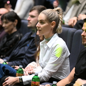 Mia čekající v sálu na odvysílání poslední epizody svého vítězství.