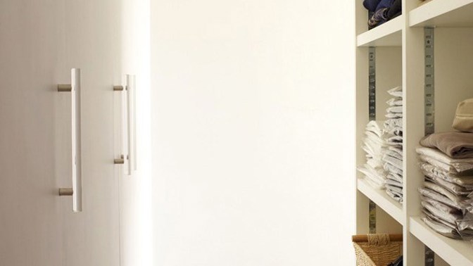 Šatní skříně svou velikostí i mnohdy masivním provedením rapidně ukrajují prostor. Anna Boyd nad touto vlastností vyzrála. Oblečení uschovala do regálů za zrcadly, které opticky zvětšily prostor před nimi. Bravo!