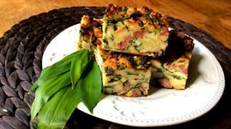 Nádivka s medvědím česnekem
Suroviny:
obyčejné rohlíky (den staré) 8 ks
mléko asi 2 dl
cibule 2 ks
jarní cibulka 2 ks
uzené maso 400 g
vinná klobása 150 g
vejce natvrdo 3 ks
čerstvý medvědí česnek 2 velké hrsti
baby špenát 2 velké hrsti
mandle (plátky, hranolky nebo nahrubo nasekané) 80 g
vejce 6 ks
kypřicí prášek 1/2 sáčku
muškátový oříšek
sůl a čerstvě namletý pepř
máslo na vymazání formy
Postup:
Rohlíky nakrájejte na menší kostičky o hraně asi 1,5–2 cm a dejte je do velké mísy. Zalijte je mlékem a promíchejte. Rohlíky by neměly být úplně namočené, spíš jen lehce zvlhlé.
Na pánvi rozehřejte trochu másla a orestujte na něm dosklovata nahrubo nakrájenou cibuli a jarní cibulku, poté přidejte na centimetrové kostičky nakrájené uzené maso a chvíli opékejte, potom vypněte oheň a směs nechte chladnout.
K rohlíkům vymačkejte ze střívka syrovou vinnou klobásu, přidejte na kostky nakrájená vařená vejce a nasekaný medvědí česnek a špenát. Také vmíchejte oloupané a nasekané mandle.
V menší misce lehce rozšlehejte syrová vajíčka, přidejte asi 1–2 lžičky soli, čerstvě namletý pepř a nastrouhaný muškátový oříšek. Poté zašlehejte kypřicí prášek. Vaječnou směs vlijte do velké mísy k rohlíkům, lehce promíchejte a pak pořádně promíchejte rukama, aby se směs dobře spojila.
Zapékací mísu vymažte máslem a rovnoměrně na ni naneste nádivkovou směs, nemusíte ji moc pěchovat, jen lehce zarovnat. Pečte v horkovzdušné troubě vyhřáté na 180 stupňů 40–45 minut, až bude povrch hezky opečený. Nádivku nechte před servírováním lehce zchladnout, aby se zpevnila.