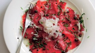 Hovězí carpaccio s kapari

Suroviny:

250 g hovězí svíčkové
mořská sůl a drcený černý pepř
1 lžíce olivového oleje
50 g kaparů v soli
4 nakládané cibulky, na tenká kolečka
3 hrsti nasekané hladkolisté petrželky
extra panenský olivový olej na zakapání
jemně strouhaný parmazán, k podávání

Postup:

Maso posypte solí a pepřem, zabalte do plastové fólie.

Svíčkovou dejte na hodinu do mrazáku, nebo na tak dlouho, aby skoro zmrzla (bude se lépe krájet na opravdu papírově tenká kolečka; nebojte se, velmi rychle roztají). Olej zahřejte na pánvi, vsypte kapary a 3–4 minuty je opékejte dokřupava. Osušte na ubrousku a nechte zchladnout.

Vybalte maso a nakrájejte ho velmi ostrým nožem na teninké plátky. Na čtyři talíře naaranžujte maso, opečené kapary, cibulku a petrželku. Zakapejte olivovým olejem, posypte parmazánem a ihned podávejte.
