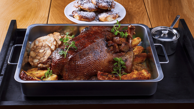 Postup:
1.	Den před pečením husu očistěte, osolte, posypejte kmínem-vmasírujte do kůže a nechte přes noc marinovat.

2.	Připravte si nádivku, chléb nakrájejte na větší kostky, stejně jako část jablek, nechte si lehce povolit sádlo a najemno nasekejte bylinky. Vše spojte a před pečením nacpěte do husy.

3.	Takto naplněnou husu vložte do hlubšího pekáče, podlijte pivem, přiklopte a vložte do předem předehřáté trouby na 90 stupňů.

4.	Ráno zvyšte teplotu na 160 stupňů a husu občas přelévejte výpekem. Hodinu před podáváním slijte výpek a teplotu zvyšte na 220 °C. Pečte do zlatova.

5.	Výpek sceďte, svařte na 1/3 a zašleháním másla upravte na preferovanou konzistenci.

6.	Uvařené brambory na škubánkové placky nechte vychladnout a nastrouhejte. Přidejte veškeré ingredience a vypracujte vláčné těsto.

7.	Na pomoučené pracovní desce vyválejte pláty zhruba 1 cm tlusté a vykrajovátkem vykrajujte škubánkové placky. Ty poté osmahněte nasucho na pánvi, ihned potřete výpekem z husy.

8.	Brambory na šišky oloupejte a uvařte je v osolené vodě hodně doměkka. Slijte je a přímo v hrnci, ve kterém se vařily, je hned promíchejte s moukou a krupicí. Hrnec přikryjte pokličkou a nechte chvíli stát – pára prostoupí moukou a šišky budou krásně držet pohromadě.

9.	Do hrnce s bramborami přidejte vejce, osolte a šťouchadlem zpracujte hladké těsto. Pomocí dvou lžic tvarujte šišky, házejte je do vroucí osolené vody a 5–7 minut vařte. Šišky ve vodě občas zamíchejte, aby se nepřilepily ke dnu hrnce.

10.	Po uvaření šišky opečte na pánvi s máslem dozlatova.

11.	Na másle orestujte nadrobno nakrájenou červenou cibuli, přisypte cukr a nechte zkaramelizovat. Přidejte červené zelí a najemno rozdrcený hřebíček, podlijte vínem a duste doměkka.

12.	Na másle orestujte bílou cibuli, přidejte jablko, cukr, tymián, potom vývar a pivo, duste doměkka, dochutíme dle potřeby solí, pepřem a cukrem.

13.	Žemle na žemlové knedlíky zastříkneme mlékem, necháme nabobtnat, přidáme mouku, žloutky, nasekanou petržel, sůl a koření. Z bílků ušleháme tuhý sníh, který vmícháme do připravené hmoty. Tu podle klasického receptu vkládáme na bavlněný šátek přetřený olejem, stočíme do válečku a na koncích zavážeme provázkem. Vložíme do vroucí vody a 15 - 20 minut vaříme. Místo šátku je možno použít alobal.


14.	Hotovou husu podávejte se zelím, škubánkovými plackami, žemlovými knedlíky a bramborovými šiškami. Husí hostinu lze doplnit pečenými jablky, které posypeme krupicovým cukrem a skořicí , opečeme společně s husou v poslední fázi jejího pečení.
