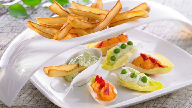 Čekankové lodičky

Suroviny:

400 g McCain Fri'Style, 1 čekanka, 200 g čerstvého tvarohu, 1 svazek čerstvých bylinek (petrželka, kerblík, meduňka atp.), 2 kusy filé z ančoviček, 1 lžička hořčice, 50 ml olivového oleje, 12 hrášků na ozdobu, 50 ml ajvaru (paprikového pyré), 1 lžička mletého kmínu (nejlépe římského), sůl, pepř, červená paprika

Postup:

Čekanku rozebereme na jednotlivé lístky. Bylinky omyjeme, osušíme a nadrobno nasekáme. Ančovičkové filé nasekáme na stejně drobné kousky. Vše spojíme s hořčicí, olivovým olejem a polovinou tvarohu. Hmotu přendáme do cukrářské stříkačky a s její pomocí nanášíme na listy čekanky. Ozdobíme hráškem. Ajvar spojíme se zbylou částí tvarohu a dochutíme solí, pepřem a kmínem. Hmotu nanášíme na listy čekanky. Papriku omyjeme, přeřízneme napůl, odstraníme jádřince a podélně nakrájíme na proužky o šířce 1 cm. Použijeme k ozdobení. McCain Fri'Style připravíme podle pokynů na obalu. Podáváme spolu s dipy na čekance.
