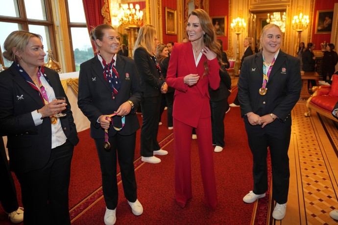Kate Middleton přivítala na hradě Windsor anglické mistryně světa v rugby v červeném kalhotovém kostýmu z dílny Alexandera McQueena. Barvou demonstrovala nejen svůj status, ale také odkazovala na přezdívku týmu, který zní Rudé růže.