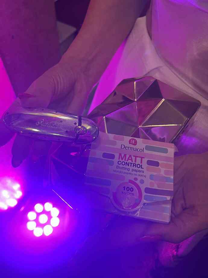 V jejím metalickém psaníčku nechyběla luxusní rtěnka se stříbrným pouzdrem a oblíbené ubrousky proti mastnotě. 