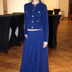 Modelka oblékla tmavě modrý komplet širokých kalhot s vysokým pasem a propínacího svetříku se zlatými knoflíky. 