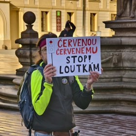 Muž před Pražským Hradem s transparentem.