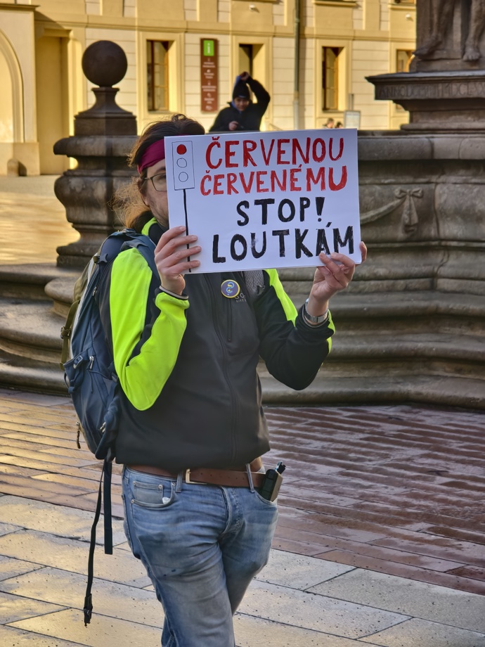 Muž před Pražským Hradem s transparentem.