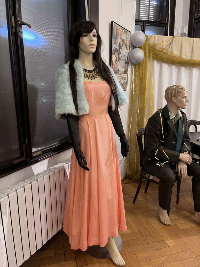 Broskvové šaty, doplněné o kontrastní černé rukavičky 